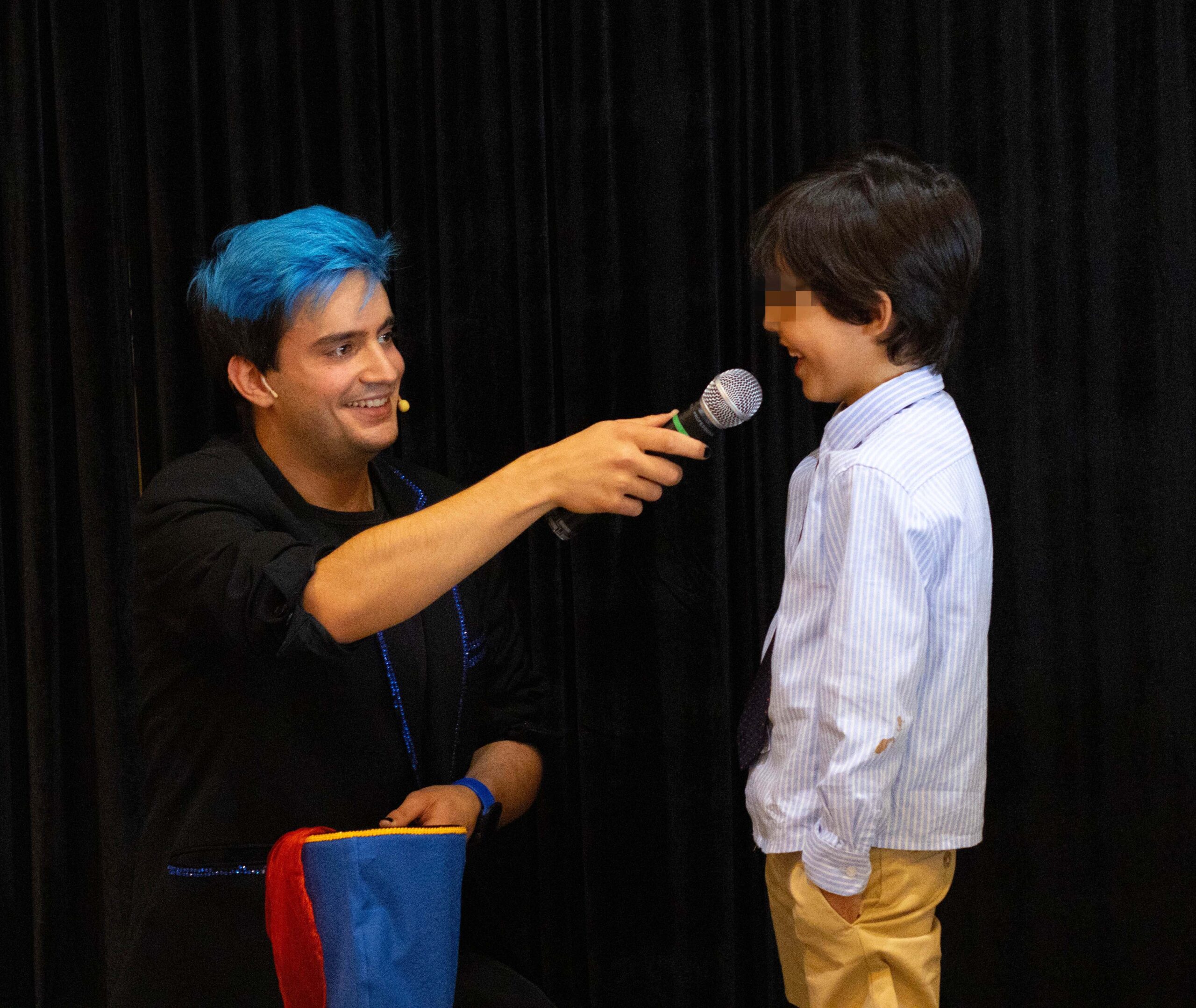 El mago para comuniones Ivan torres con un niño acercandole el micro para hablar.