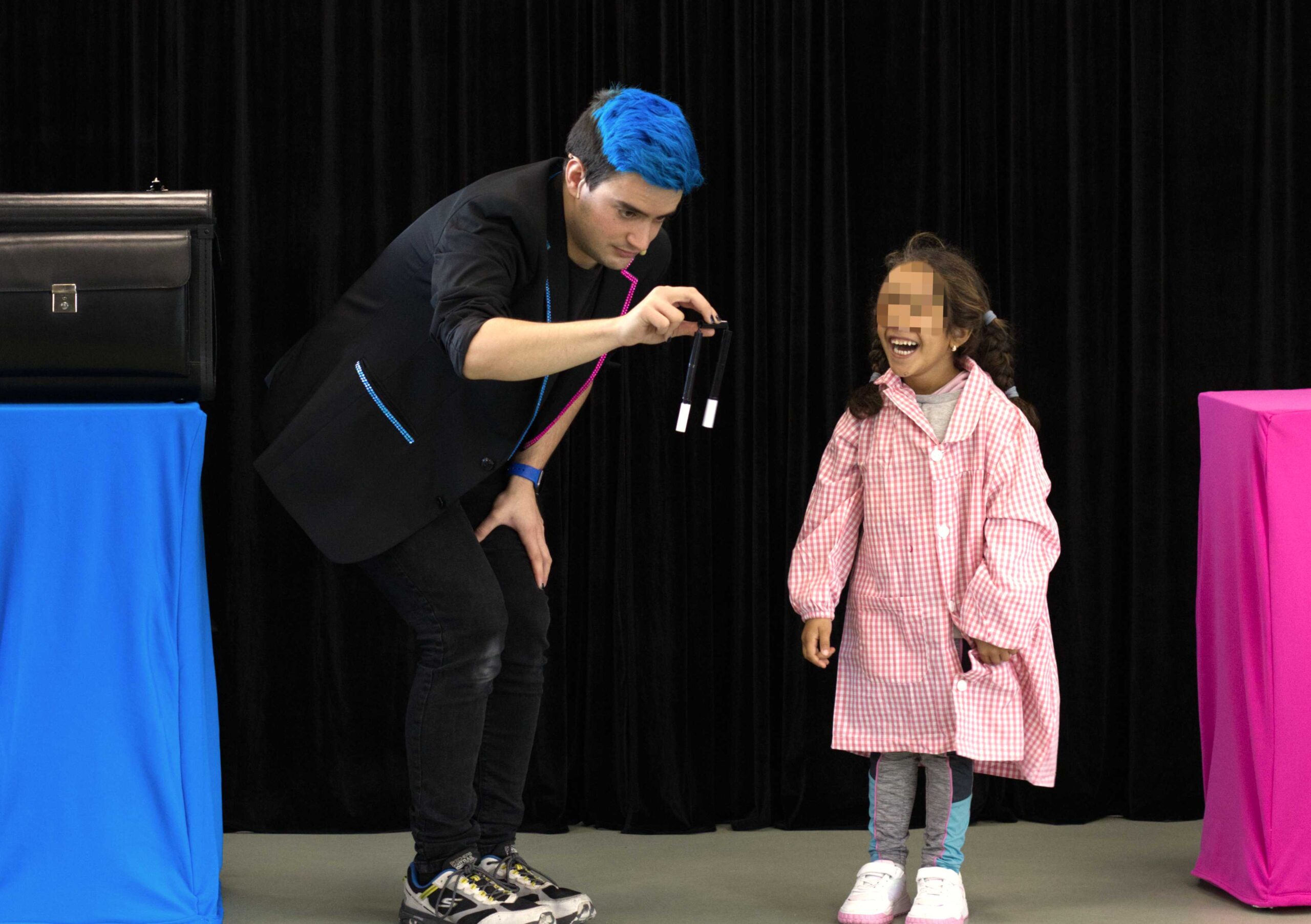 El mago para colegios Ivan Torres con una niña donde se ve sujetando una varita rota y la niña riéndose. Actividad educativa original para colegios.
