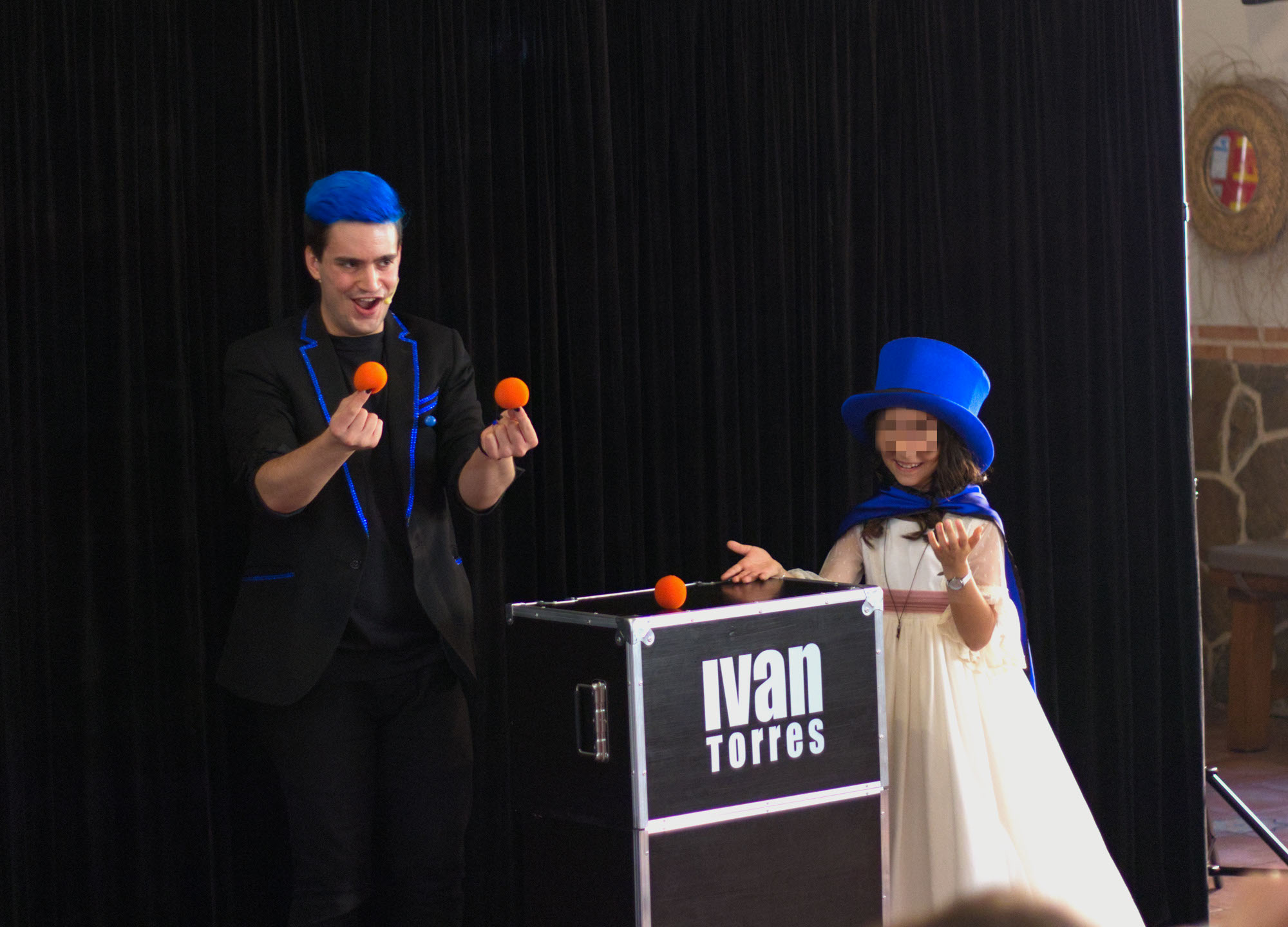Mago Comuniones Ivan Torres con dos bolas naranjas en la mano junto a la niña de la comunión flipando