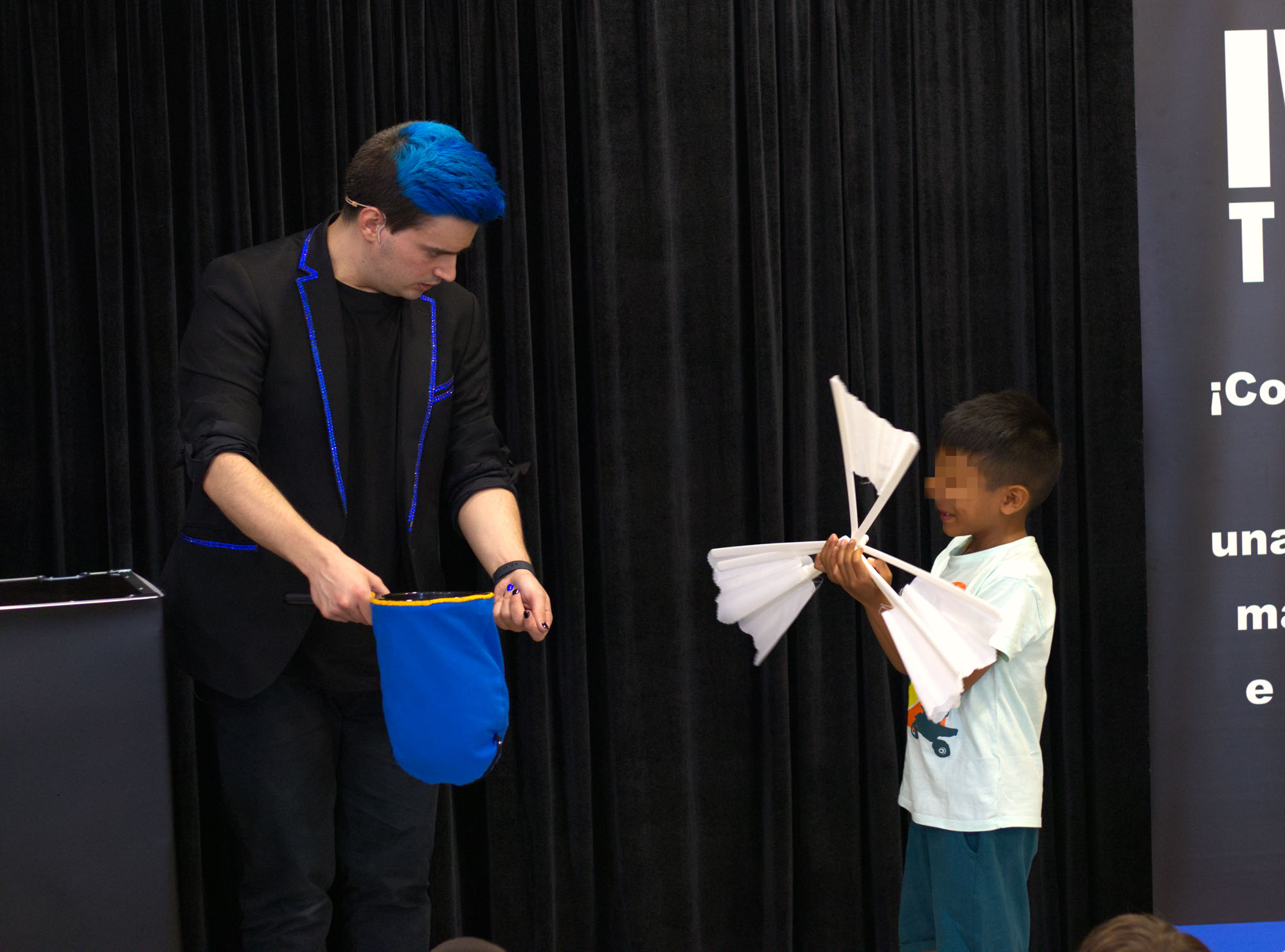 Niño con un abanico roto mientras el mago para cumpleaños Ivan Torres sujetando una bolsa azul