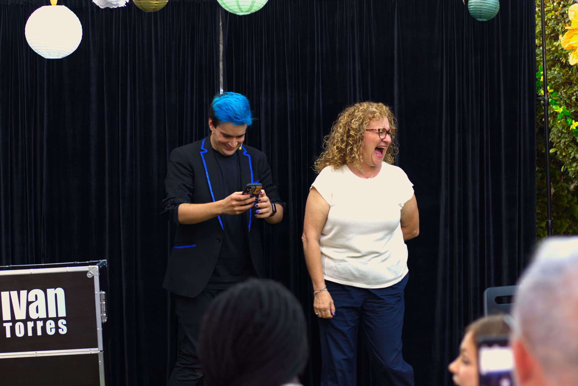 Ivan Torres escribiendo en un teléfono mientras espectadora a su lado se ríe de una broma