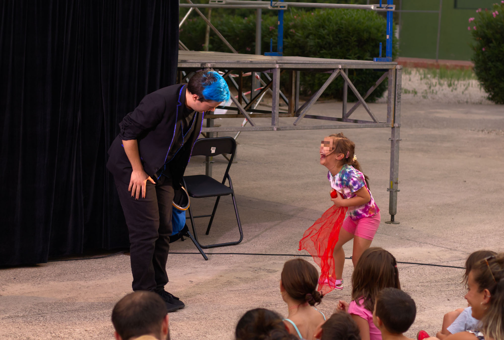 Ivan Torres - Mago para eventos y empresas mirándo a una niña que se está riéndo mientras sujeta un pañuelo rojo