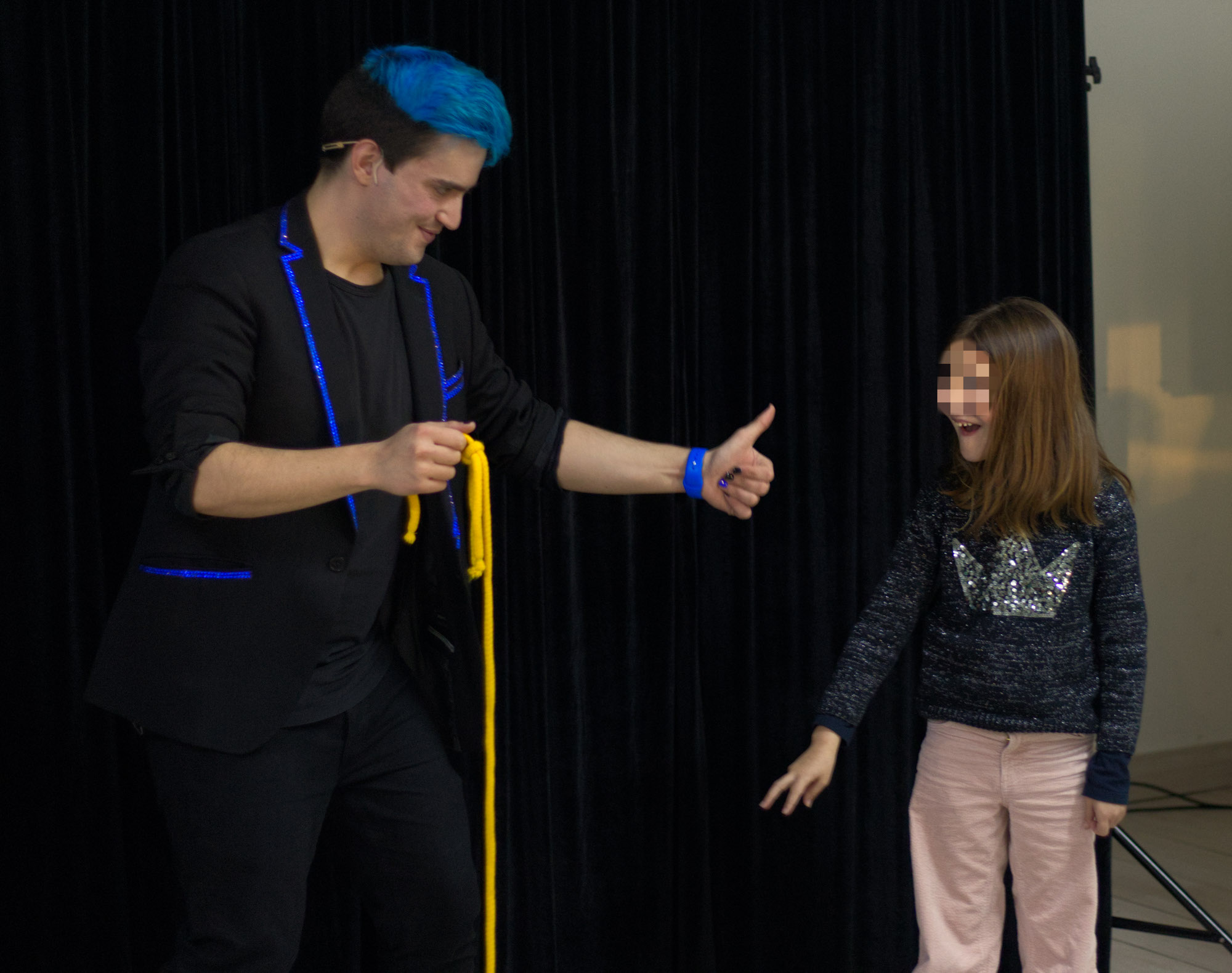 Momento del show donde el mago para eventos Ivan Torres está con una cuerda y una niña al lado sorprendida. con la magia