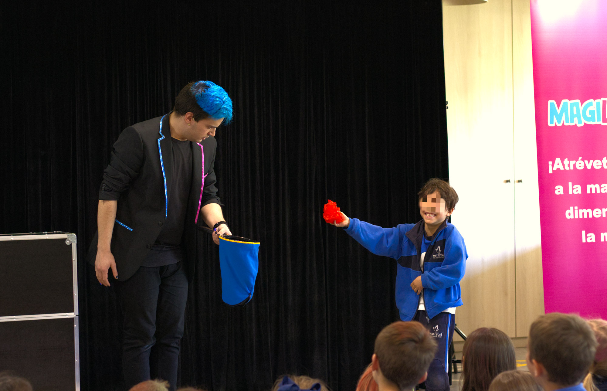 Mago para eventos Ivan Torres actuando en las fiestas de un colegio y un niño al lado riéndose con un pañuelo rojo en la mano