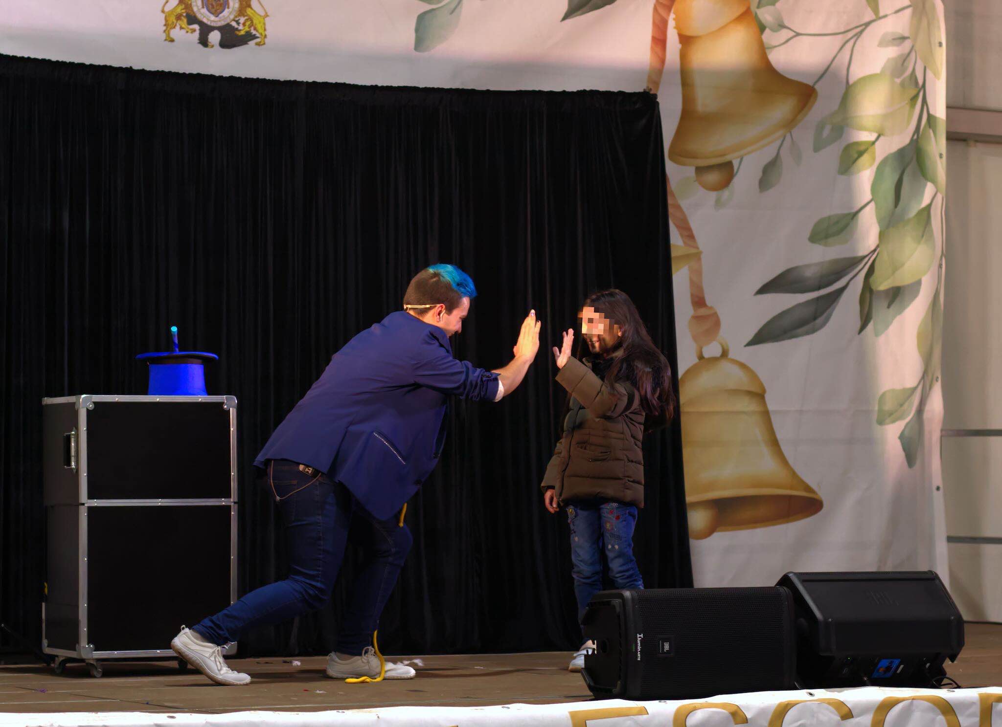 El mago Ivan Torres interactuando con una niña en el escenario.
