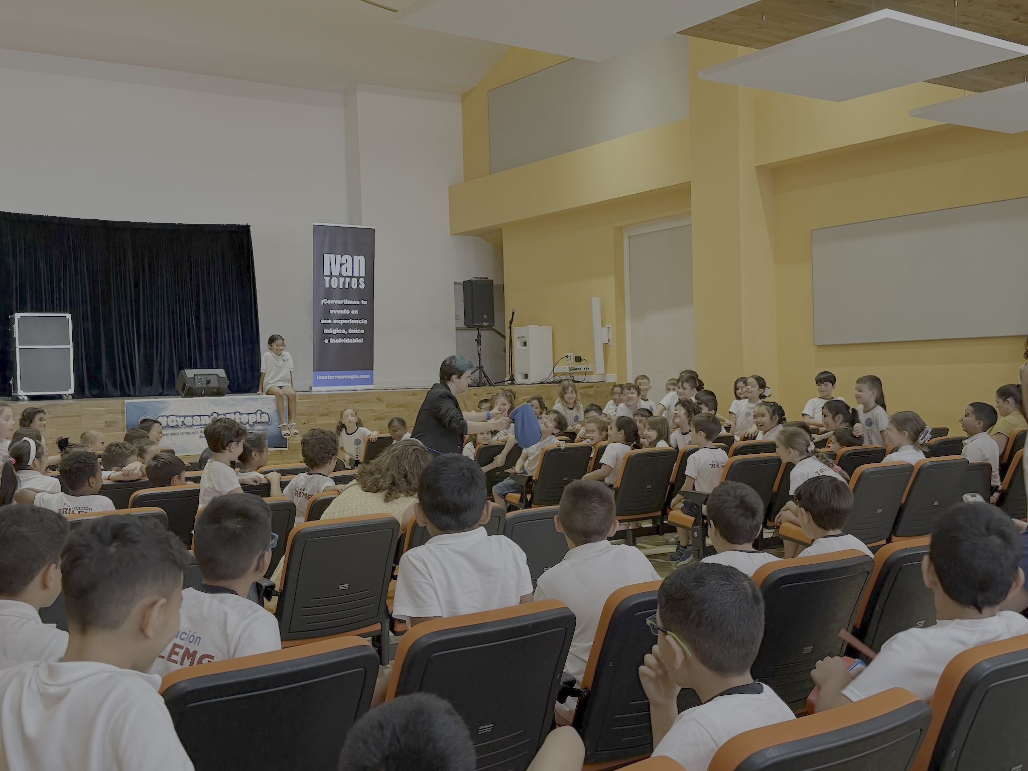 El mago Ivan Torres cautiva a un grupo de niños en auditorio.